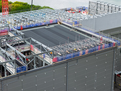 Aerial view of a data center under construction featuring a large steel frame structure, scaffolding, and a flat roof, United Kingdom.