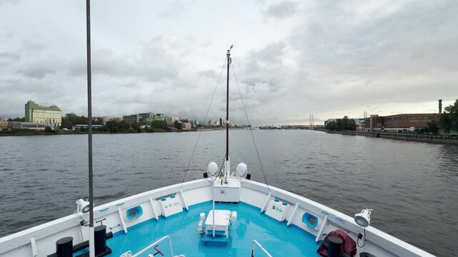 A white cruise ship bow glides along the wide river waters. The vast open perspective inspires a calm, peaceful, and adventurous feeling under cloudy skies.