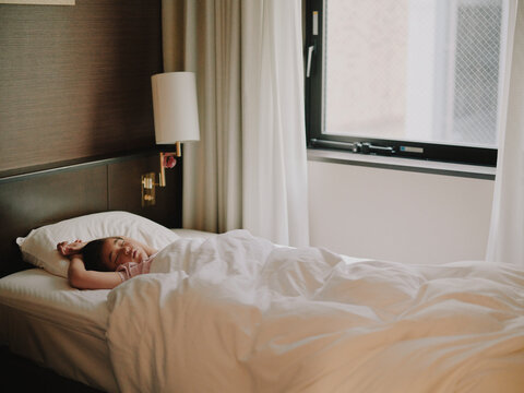Young child sleeping peacefully in a hotel bed in morning light
