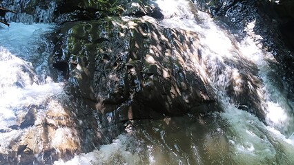 Waterfall cascading over moss covered rocks in natural forest setting © md