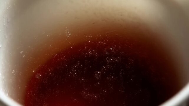 Hot tea gently rippling inside a ceramic cup in an extreme close-up. Tea advertising, beverage packaging promotion, and cafe marketing.