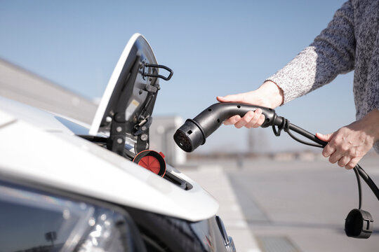 Data Set Training &ndash; woman charging electric car with EV charging station. Parking area background, providing a realistic everyday environment for electric vehicle charging.