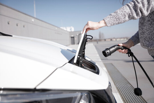 Data Set Training &ndash; woman charging electric car with EV charging station. Parking area background, providing a realistic everyday environment for electric vehicle charging.