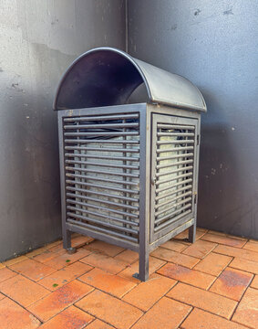 Photograph of a steel rubbish bin securely bolted to a brick footpath at a popular commercial shopping centre in a regional town in New South Wales, Australia