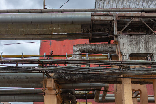 Industrial pipes, cables, infrastructure at manufacturing plant. Urban decay, infrastructure complexity, utility systems, energy, maintenance.
