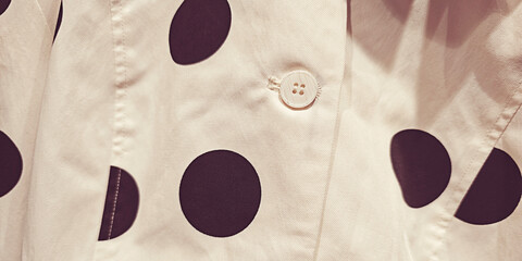 This design features classic black polka dots on a white fabric, complete with a petite button for added charm. The pattern and texture offer a timeless appeal © Bonsales