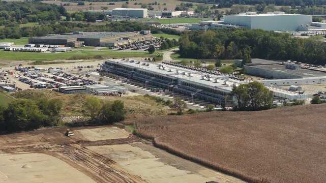 Drone aerial establishing view of large white data center construction being built in central Ohio by Springfield, OH near countryside rural country landscape of tech data building for AI hardware 4k