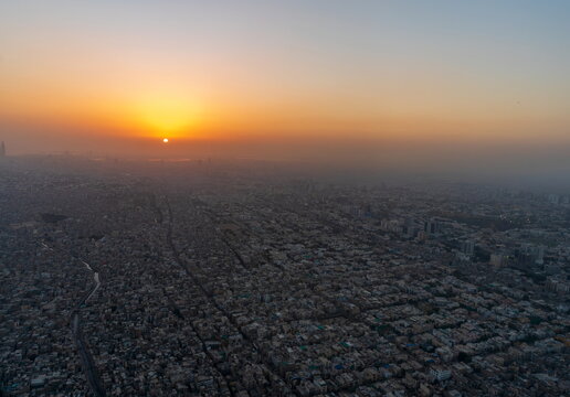 Aerial view of the dense urban sprawl of Karachi at sunset with golden light casting long shadows over the rooftops in Karachi, Sindh, Pakistan.