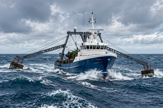 Modern fishing trawler at sea with large steel outriggers deployed.