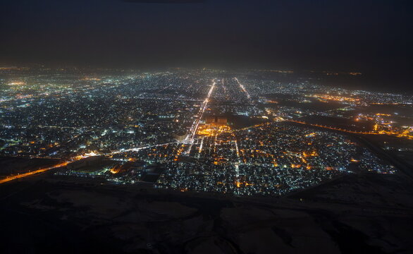 Aerial view of the sprawling city lights of Karachi at night, with illuminated streets and dense urban infrastructure stretching across the landscape in Karachi, Sindh, Pakistan.