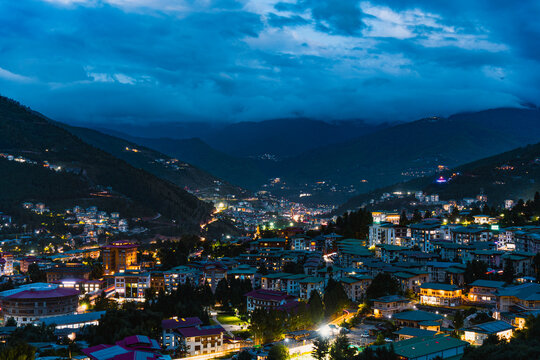 City view of Thimphu, Bhutan, Viewpoint on SEP 2026, Nighttime view of illuminated hillside town with cloudy sky and mountains, sustainability, zero carbon, negative carbon