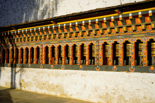 Changangkha Lhakhang, Ornate traditional prayer wheel row with vibrant decoration on stone wall