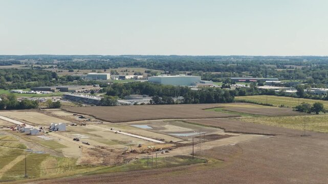 Drone aerial establishing view of large white data center construction being built in central Ohio by Springfield, OH near countryside rural country landscape of tech data building for AI hardware 4k
