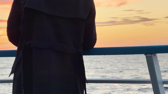 A person in a coat stands at a ship railing overlooking Lake Ladoga at sunset. The golden sky creates a serene and reflective mood. The view brings a feeling of quiet peace.