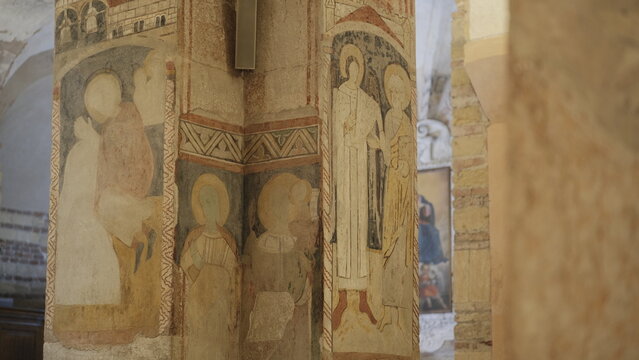 Ancient religious frescoes on stone pillars inside the Romanesque crypt of San Fermo Church in Verona, Veneto.