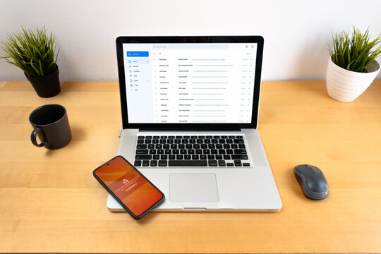 Smartphone with unusual login warning beside laptop email interface