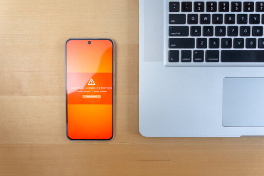 Flat lay smartphone showing unusual login warning beside laptop