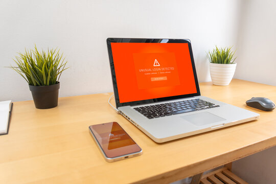 Unusual login warning displayed on phone and laptop on wooden desk