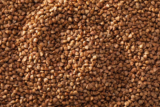 Texture of buckwheat groats, brown kernels filling full frame, top view, natural food background