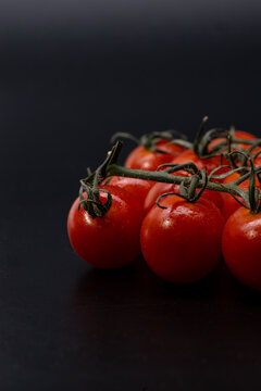 Cherry tomatoes on the vine with dark vertical copy space