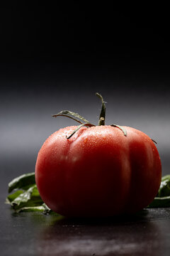 Ribbed tomato with water droplets and dark copy space