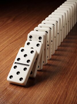 Falling dominoes in a row, domino effect, chain reaction on a wooden table