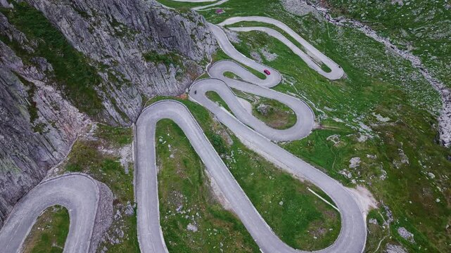 Top-down aerial drone footage of the Tremola hairpin road on the Gotthard Pass, Switzerland, with slow forward flight over historic cobblestone switchbacks