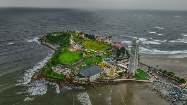 Aerial view of the Murudeshwar Temple complex featuring the massive Shiva statue and the towering Raja Gopura, surrounded by the Arabian Sea in Murdeshwar, Karnataka, India.