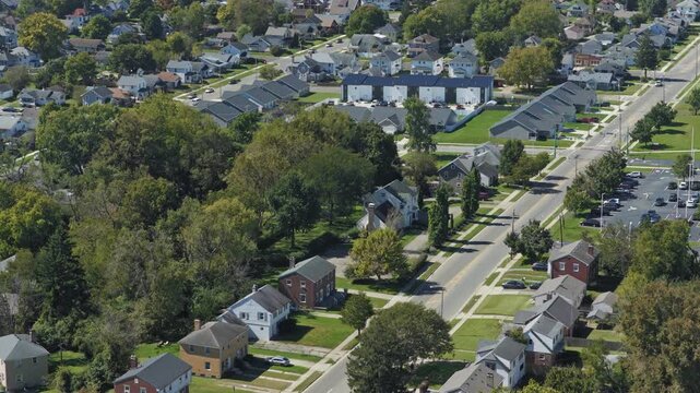 Drone aerial view of suburban rural neighborhood homes, houses,  neighbors, and family residential units in housing market by central Ohio city town Springfield, OH by countryside roads and streets 4k