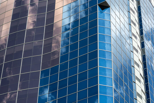 Glass facade of modern office building with sky reflection