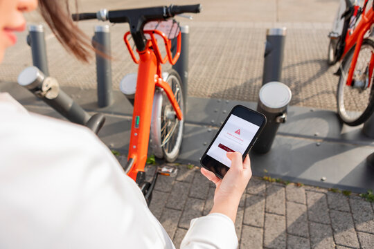 Woman use smartphone to rent electric bike in city