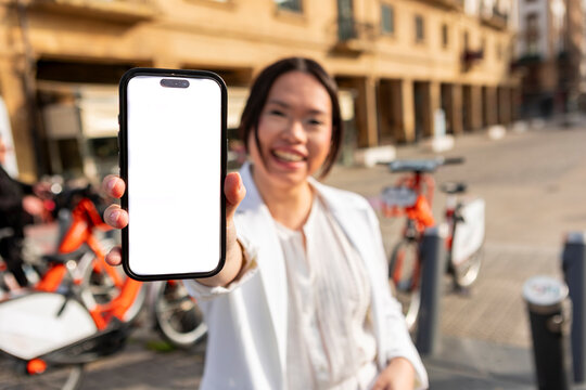 Asian woman show blank smartphone screen near rental bicycle