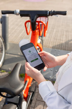 Smartphone confirms electric bicycle rental in city street