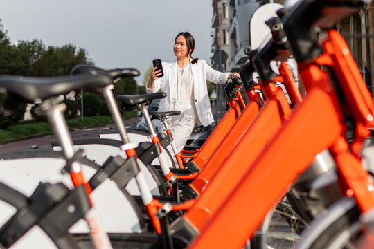 Woman unlocks shared bicycle with smartphone in city