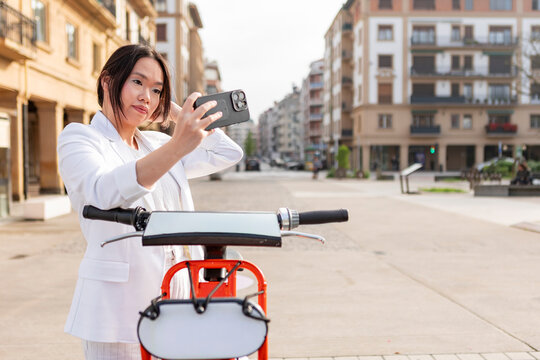 Woman take selfie on electric scooter in city street