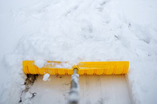 Yellow snow shovel clearing a path in winter