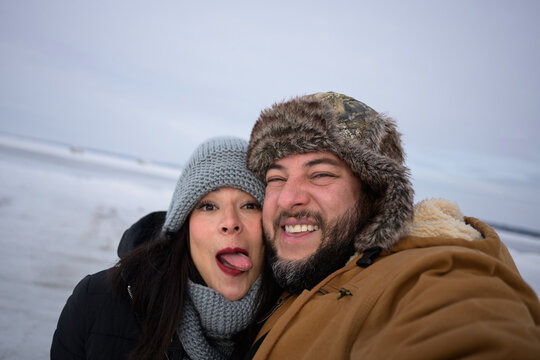 Playful winter selfie of couple at Sylvan Lake, Alberta