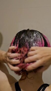 Washing and massaging hair with pink highlights in a shower setting