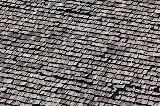 Rustic architecture and traditional craftsmanship weathered wooden shingle roof texture on a mountain cabin in the Alps