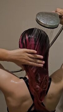 Woman washing hair in shower with water and shampoo application