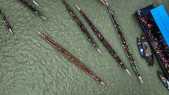 Baghabari, Bangladesh - 20 August 2022: Aerial view of long traditional boats competing in a boat race on the river with many rowers paddling in unison.