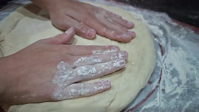 Hands kneading dough on a floured surface in a kitchen setting over time