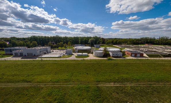 Opole, Poland - 06 September 2026: Aerial view of the wastewater treatment plant near the Oder river, featuring circular sedimentation tanks, industrial buildings, and green spaces.
