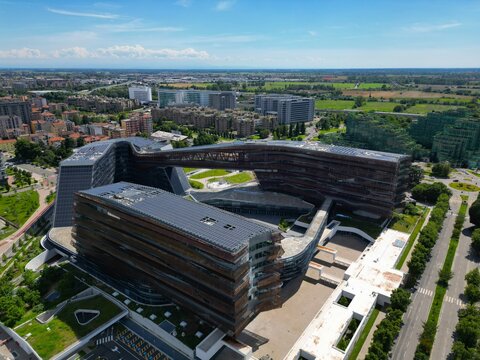 Modern Architectural Complex: An aerial view showcases a sprawling, modern architectural complex with unique curved design and glass facades, Milan, Italy