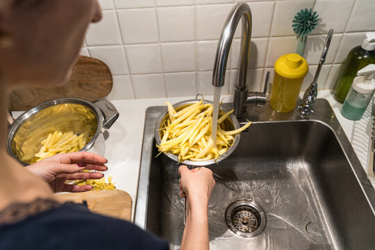 Woman rinse yellow beans in kitchen sink for dinner
