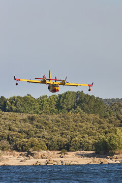 Yellow firefighting plane fly low over coastal forest