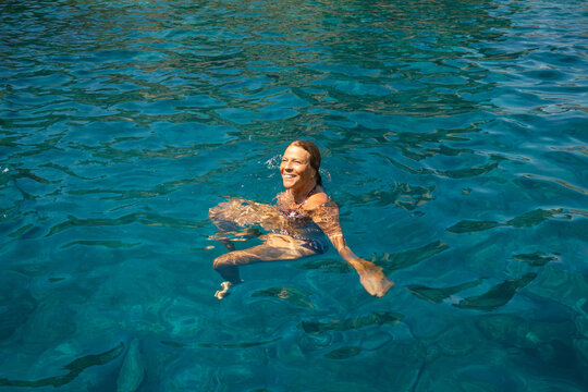 Smiling woman swim in clear blue tropical ocean water