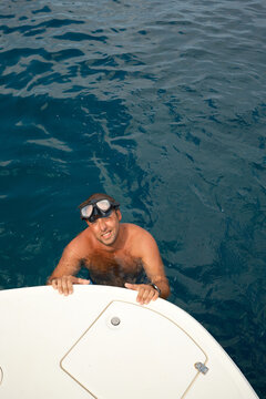Man in diving goggles beside boat in open water
