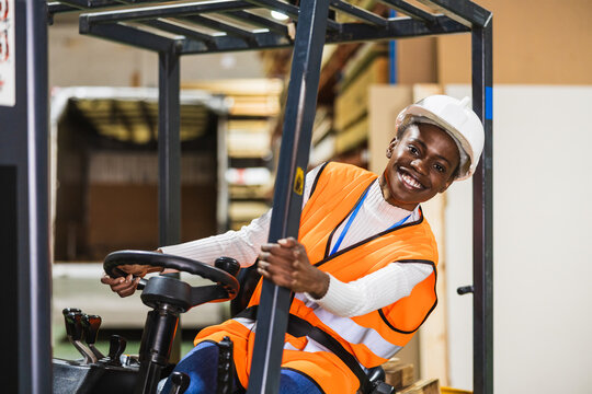 Happy worker driving forklift in lumberyard warehouse