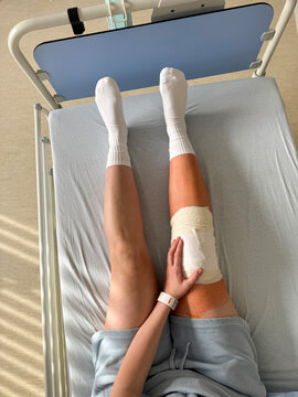 Patient with bandaged knee resting in hospital bed